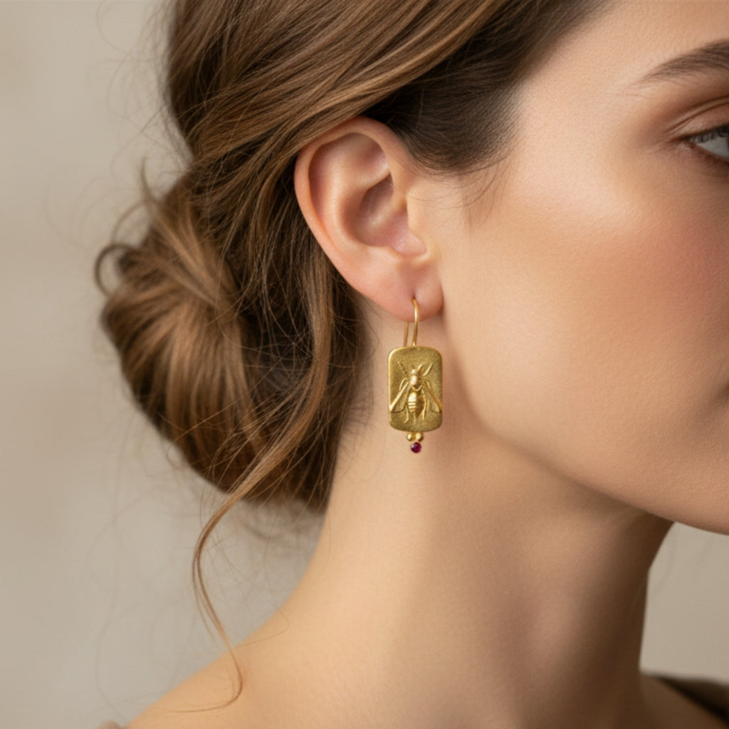 Close-up of bee coin earrings, red topaz gemstone detail, artisan gold plated 925 silver, Turkish designer jewelry
