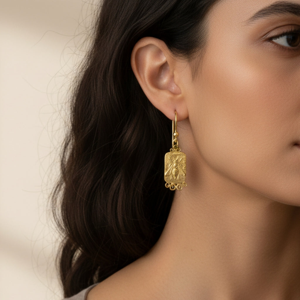 Close-up of Turkish artisan bee coin earrings with green peridot showing detailed 24K gold plating, handcrafted in Bodrum atelier
